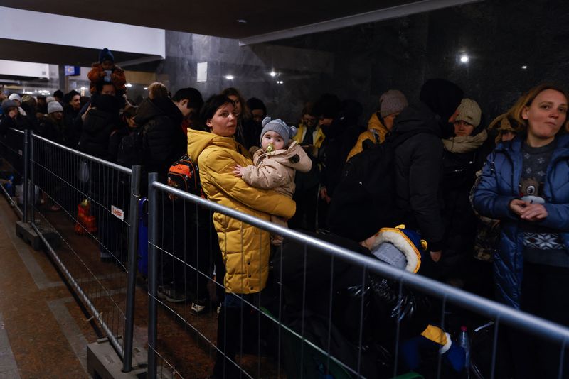 Mulher segura criança enquanto pessoas fugindo da invasão russa à Ucrânia fazem fila em Lviv, na Ucrânia eua ajuda