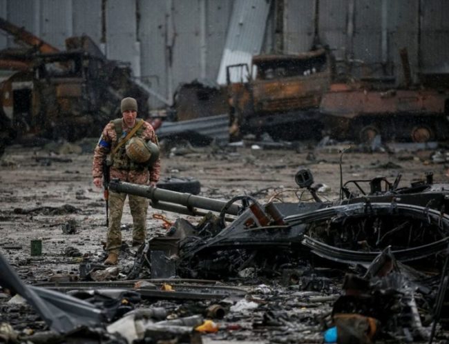 Soldado ucraniano observa destroços nos arredores de Kiev